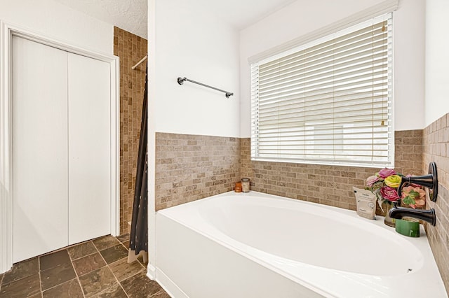 129 Breezy Shore Ct, Dickinson, TX 77539 - full bathroom featuring a bath, a shower with curtain, stone finish floors, tile walls, and a wainscoted wall