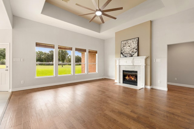 4946 Westchester Dr, Fulshear, TX 77441 - unfurnished living room featuring ceiling fan, a tray ceiling, a fireplace, wood finished floors, and a towering ceiling