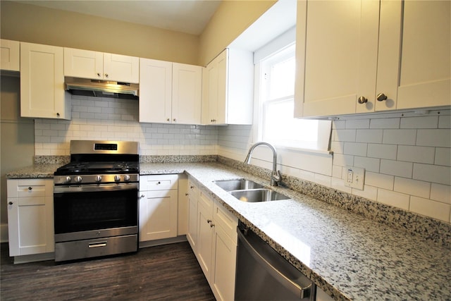 716 Olive St, Wharton, TX 77488 - kitchen with appliances with stainless steel finishes, under cabinet range hood, light stone countertops, dark wood-type flooring, and white cabinets