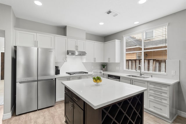3423 Velasco Ct, Missouri City, TX 77459 - kitchen with stainless steel appliances, under cabinet range hood, white cabinetry, light countertops, and light wood-style flooring