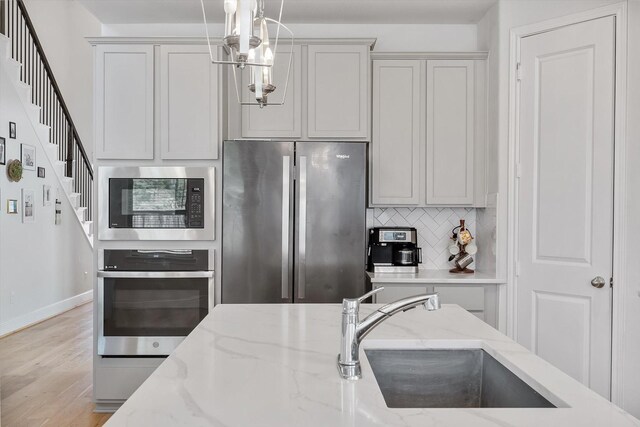 10059 Preserve Way, Conroe, TX 77385 - kitchen with appliances with stainless steel finishes, tasteful backsplash, hanging light fixtures, light wood-style floors, and light stone countertops