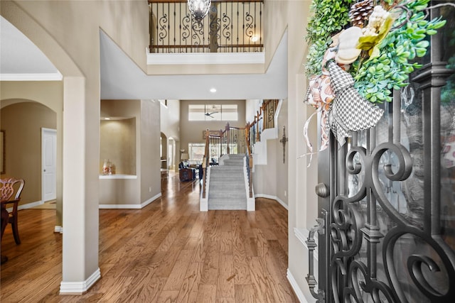 18815 Manleigh Ct, Tomball, TX 77377 - entrance foyer with arched walkways, a high ceiling, stairs, wood finished floors, and ornamental molding