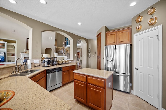 18815 Manleigh Ct, Tomball, TX 77377 - kitchen with appliances with stainless steel finishes, brown cabinets, light tile patterned floors, arched walkways, and recessed lighting