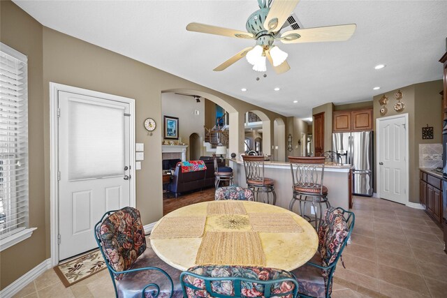 18815 Manleigh Ct, Tomball, TX 77377 - dining room with a ceiling fan, arched walkways, a fireplace, light tile patterned floors, and recessed lighting