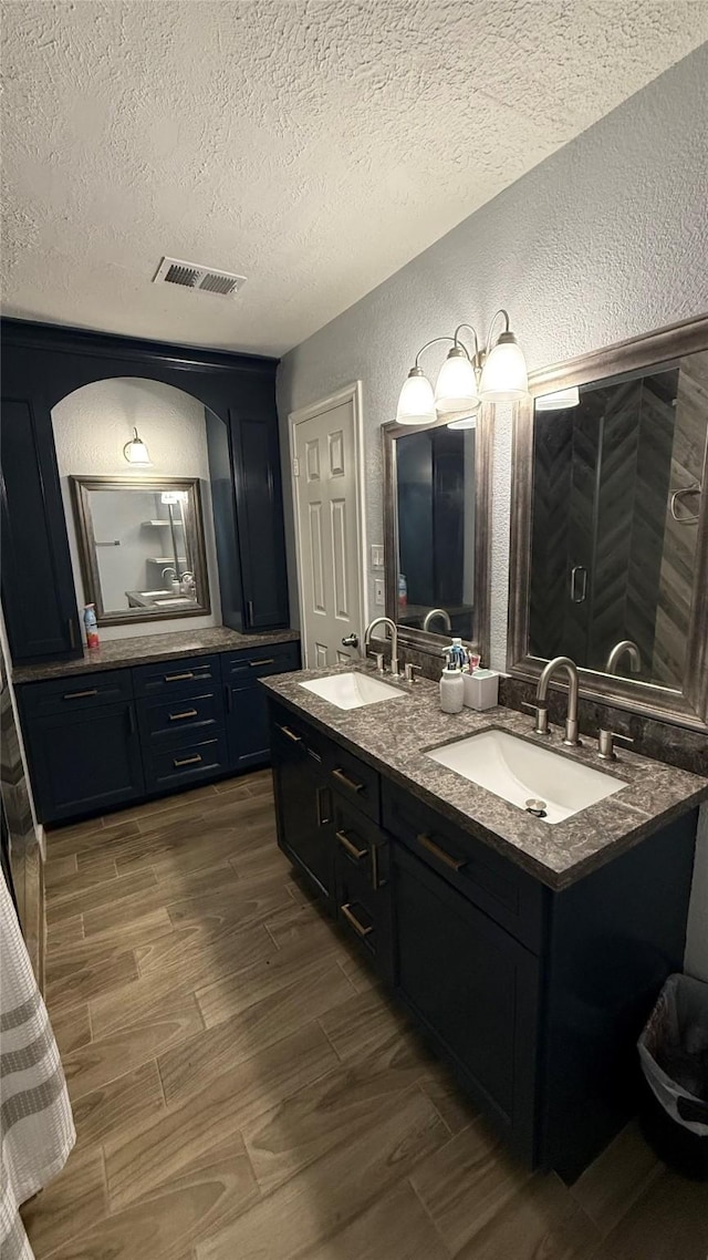 6018 Beaconridge Dr, Houston, TX 77053 - bathroom with a textured wall, a textured ceiling, double vanity, and wood finished floors