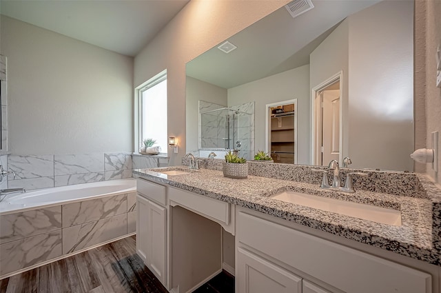 15055 Meadow Gln N, Conroe, TX 77306 - bathroom with a shower stall, double vanity, a bath, wood finished floors, and a spacious closet