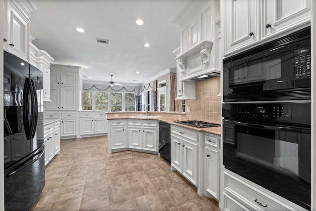 11510 Walden Rd, Montgomery, TX 77356 - kitchen featuring black appliances, a peninsula, white cabinets, backsplash, and light stone counters