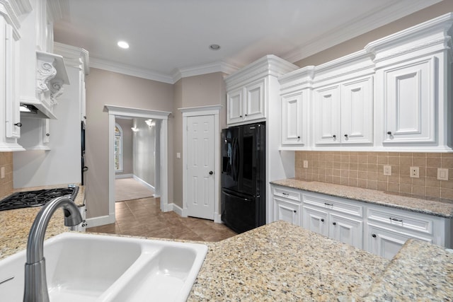 11510 Walden Rd, Montgomery, TX 77356 - kitchen with black refrigerator with ice dispenser, white cabinets, decorative backsplash, crown molding, and light stone countertops