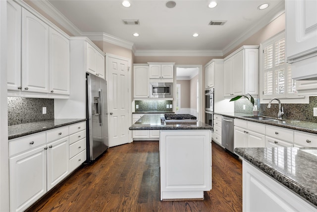 3908 Milton St, West University Place, TX 77005 - kitchen featuring stainless steel appliances, a center island, white cabinetry, dark stone countertops, and crown molding