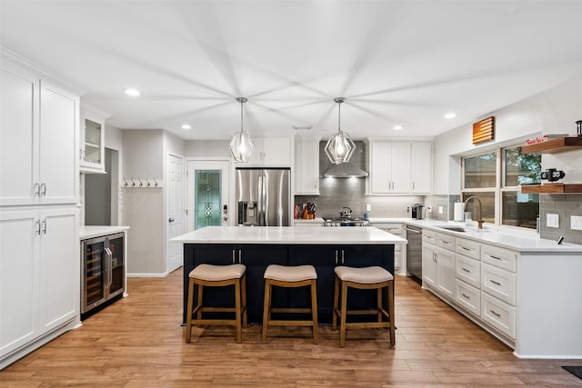7 Bending Branch Pl, Spring, TX 77381 - kitchen featuring stainless steel appliances, beverage cooler, wall chimney exhaust hood, backsplash, and recessed lighting