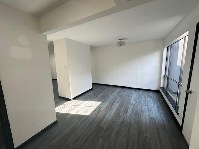 9009 Imogene St Unit E, Houston, TX 77036 - unfurnished room featuring baseboards and dark wood-style flooring