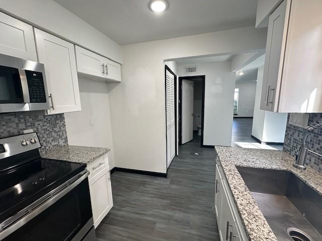 9009 Imogene St Unit E, Houston, TX 77036 - kitchen with stainless steel appliances, light stone countertops, decorative backsplash, and dark wood-style floors