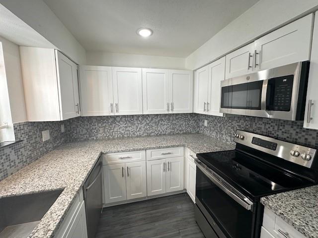 9009 Imogene St Unit E, Houston, TX 77036 - kitchen featuring stainless steel appliances, white cabinetry, dark wood-style flooring, and tasteful backsplash