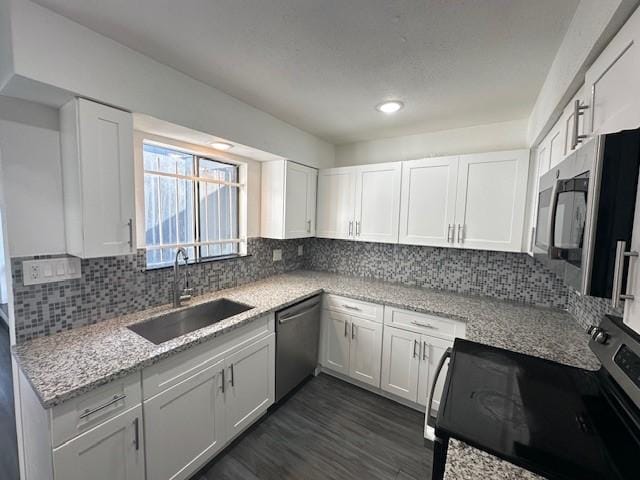 9009 Imogene St Unit E, Houston, TX 77036 - kitchen featuring stainless steel appliances, white cabinetry, and decorative backsplash