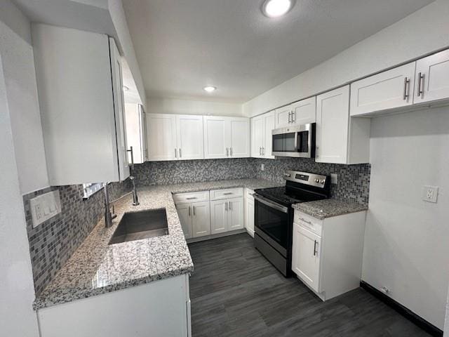 9009 Imogene St Unit E, Houston, TX 77036 - kitchen featuring appliances with stainless steel finishes, light stone countertops, white cabinetry, backsplash, and dark wood-style floors