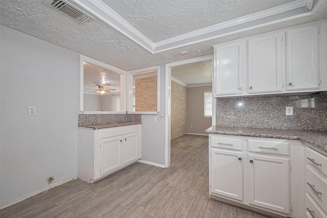 10423 Rancho Bernardo Ln, Sugar Land, TX 77498 - kitchen with a textured ceiling, light wood-style flooring, ornamental molding, white cabinetry, and tasteful backsplash