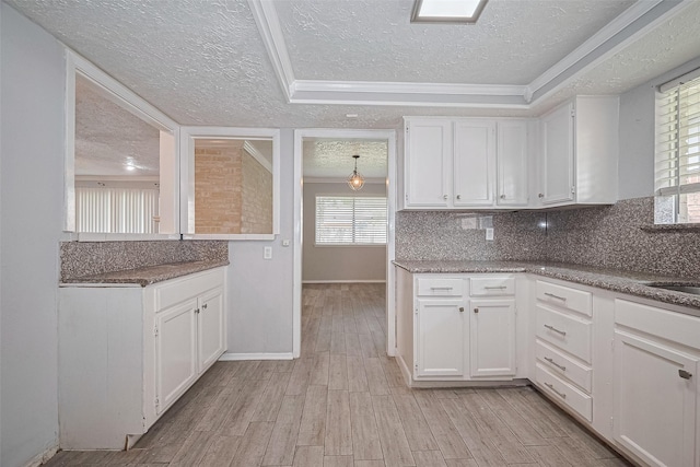 10423 Rancho Bernardo Ln, Sugar Land, TX 77498 - kitchen with a textured ceiling, white cabinetry, light wood-type flooring, backsplash, and ornamental molding