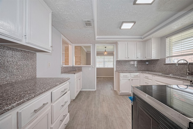 10423 Rancho Bernardo Ln, Sugar Land, TX 77498 - kitchen featuring white cabinetry, a textured ceiling, plenty of natural light, light wood-style floors, and dark stone countertops