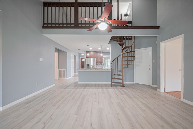 9302 Moorfield Ct, Houston, TX 77083 - unfurnished living room with a ceiling fan, stairway, light wood-style floors, and a high ceiling