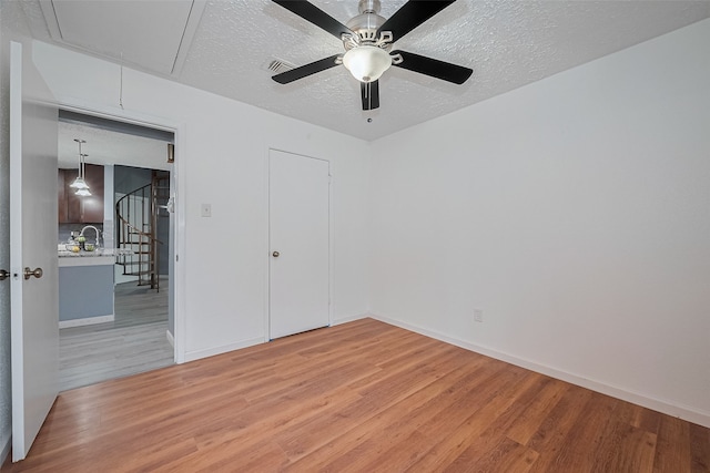 9302 Moorfield Ct, Houston, TX 77083 - unfurnished bedroom featuring attic access, light wood-style flooring, a textured ceiling, and ceiling fan