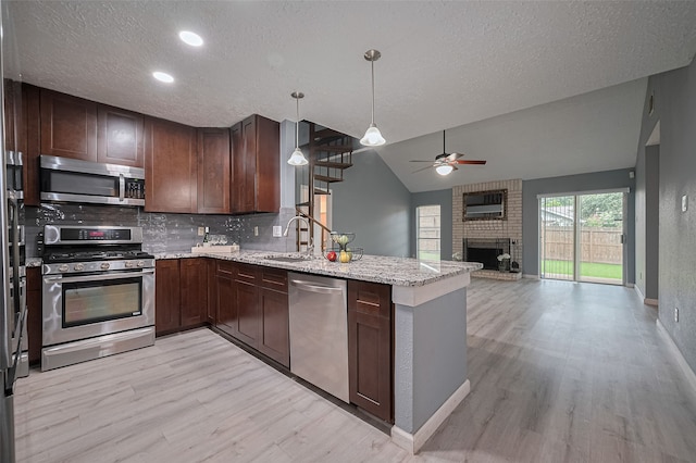 9302 Moorfield Ct, Houston, TX 77083 - kitchen featuring stainless steel appliances, ceiling fan, light wood-style flooring, a peninsula, and backsplash