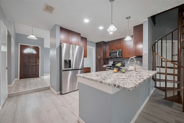 9302 Moorfield Ct, Houston, TX 77083 - kitchen featuring appliances with stainless steel finishes, light wood-style flooring, a peninsula, tasteful backsplash, and pendant lighting