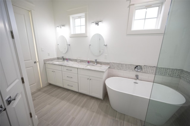 18414 Indian Beach Ct, Galveston, TX 77554 - full bathroom with a soaking tub, double vanity, wainscoting, and tile walls