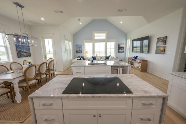 18414 Indian Beach Ct, Galveston, TX 77554 - kitchen featuring a kitchen island, black electric cooktop, stainless steel dishwasher, a chandelier, and light wood-style floors