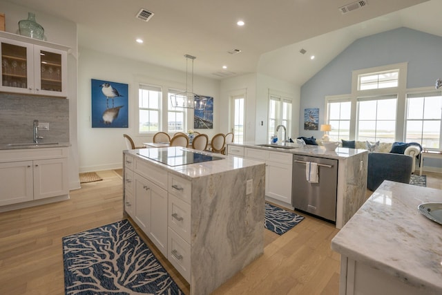 18414 Indian Beach Ct, Galveston, TX 77554 - kitchen featuring stainless steel dishwasher, a center island with sink, black electric stovetop, light wood-style flooring, and healthy amount of natural light