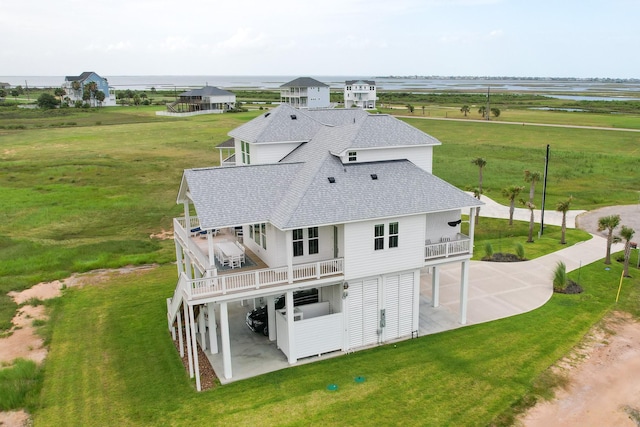 18414 Indian Beach Ct, Galveston, TX 77554 - rear view of property featuring roof with shingles, a balcony, a patio area, and a lawn