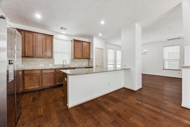 3324 Masters Point Dr, Houston, TX 77091 - kitchen featuring high quality fridge, dark wood-style floors, backsplash, brown cabinetry, and a textured ceiling