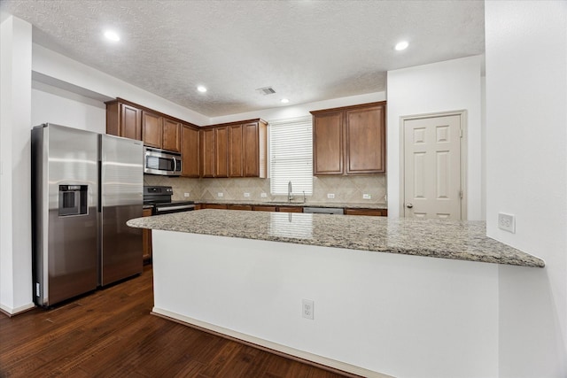 3324 Masters Point Dr, Houston, TX 77091 - kitchen with stainless steel appliances, dark wood-style flooring, light stone counters, a peninsula, and tasteful backsplash