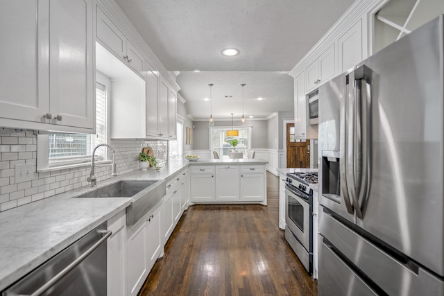 829 E 27th St, Houston, TX 77009 - kitchen featuring stainless steel appliances, a peninsula, white cabinetry, dark wood-type flooring, and recessed lighting