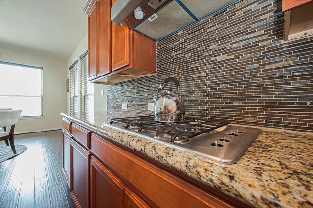 6022 Allendale Ridge Trl, Richmond, TX 77407 - kitchen featuring stainless steel gas stovetop, tasteful backsplash, brown cabinetry, light stone counters, and dark wood-type flooring