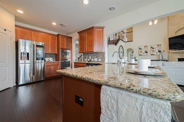 6022 Allendale Ridge Trl, Richmond, TX 77407 - kitchen with appliances with stainless steel finishes, arched walkways, light stone counters, decorative backsplash, and open floor plan