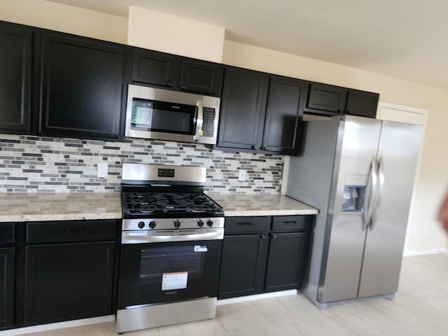 19843 Portlick Ct, Katy, TX 77449 - kitchen with stainless steel appliances, dark cabinets, and tasteful backsplash