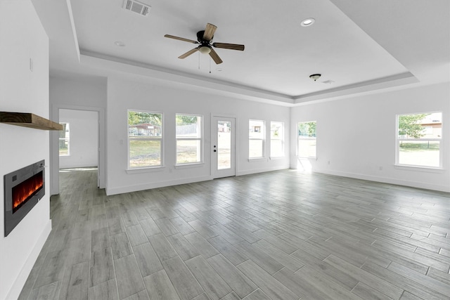 1005 Lake View Dr, Montgomery, TX 77356 - unfurnished living room featuring a raised ceiling, plenty of natural light, a lit fireplace, ceiling fan, and recessed lighting