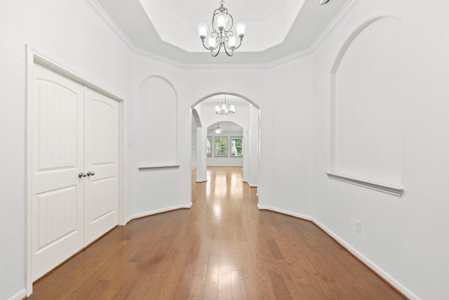1109 Jacobs Lake Blvd, Conroe, TX 77384 - hallway with arched walkways, a chandelier, a tray ceiling, hardwood / wood-style flooring, and crown molding