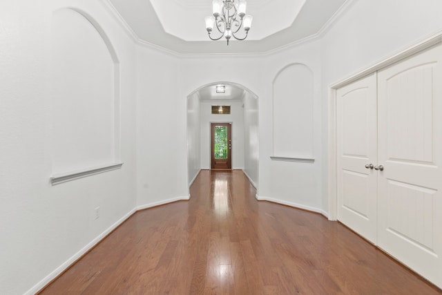 1109 Jacobs Lake Blvd, Conroe, TX 77384 - hallway with arched walkways, wood finished floors, a chandelier, a raised ceiling, and crown molding