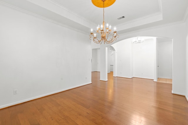 1109 Jacobs Lake Blvd, Conroe, TX 77384 - spare room featuring arched walkways, a chandelier, wood finished floors, ornamental molding, and a tray ceiling