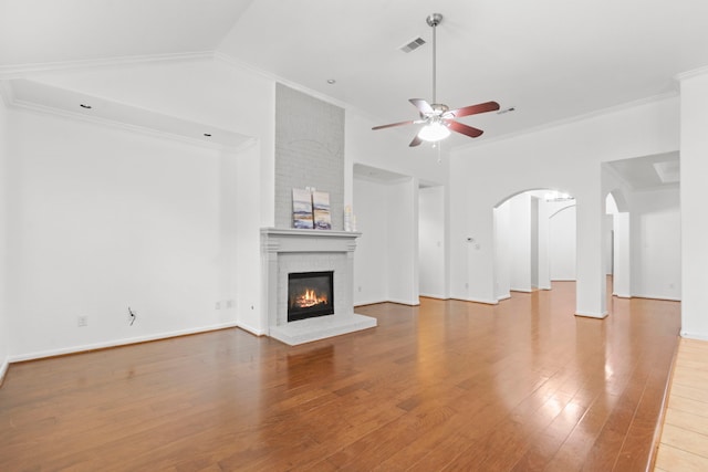 1109 Jacobs Lake Blvd, Conroe, TX 77384 - unfurnished living room with a ceiling fan, ornamental molding, wood finished floors, a brick fireplace, and arched walkways