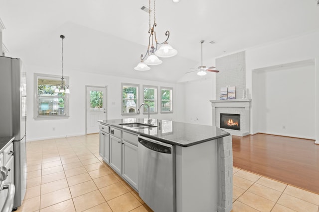 1109 Jacobs Lake Blvd, Conroe, TX 77384 - kitchen featuring stainless steel appliances, light tile patterned floors, ceiling fan, vaulted ceiling, and a fireplace