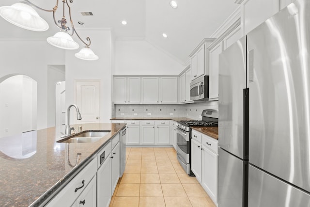 1109 Jacobs Lake Blvd, Conroe, TX 77384 - kitchen with stainless steel appliances, arched walkways, dark stone countertops, backsplash, and light tile patterned floors