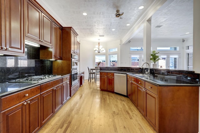 5346 Mcculloch Cir, Houston, TX 77056 - kitchen with appliances with stainless steel finishes, a chandelier, light wood-type flooring, backsplash, and hanging light fixtures