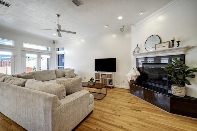 5346 Mcculloch Cir, Houston, TX 77056 - living room featuring crown molding, a ceiling fan, light wood-style floors, recessed lighting, and a glass covered fireplace