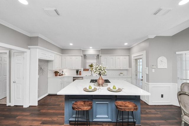 8618 Aldeburgh Ct, Spring, TX 77379 - kitchen featuring light countertops, white cabinets, dark wood-type flooring, a breakfast bar, and wainscoting