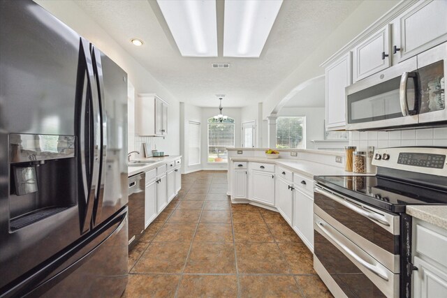 18518 Autumn Park Dr, Houston, TX 77084 - kitchen with appliances with stainless steel finishes, backsplash, a peninsula, arched walkways, and light countertops