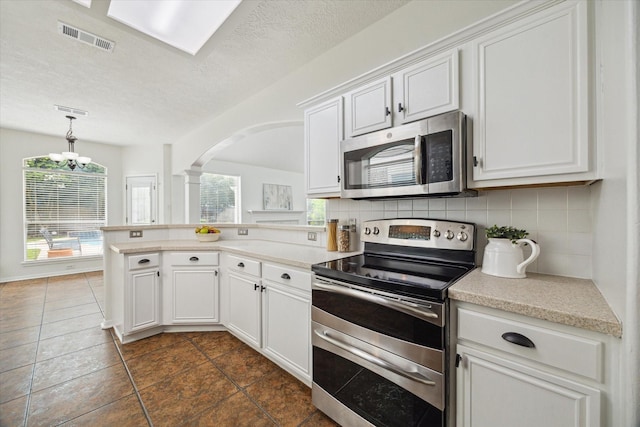 18518 Autumn Park Dr, Houston, TX 77084 - kitchen with appliances with stainless steel finishes, arched walkways, a peninsula, light countertops, and tasteful backsplash