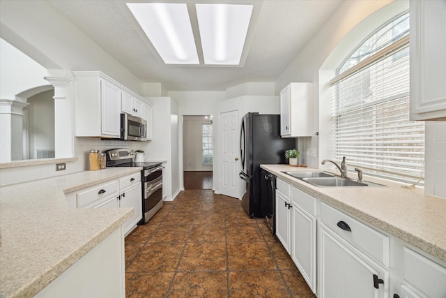 18518 Autumn Park Dr, Houston, TX 77084 - kitchen with stainless steel appliances, ornate columns, light countertops, white cabinets, and backsplash