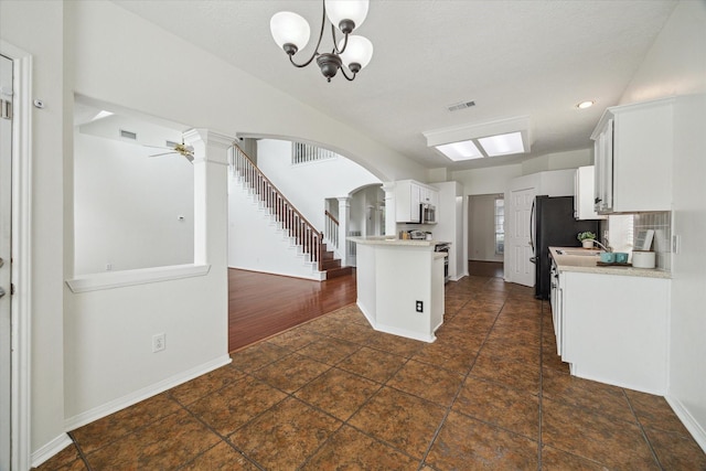 18518 Autumn Park Dr, Houston, TX 77084 - kitchen featuring light countertops, arched walkways, white cabinets, stainless steel microwave, and recessed lighting